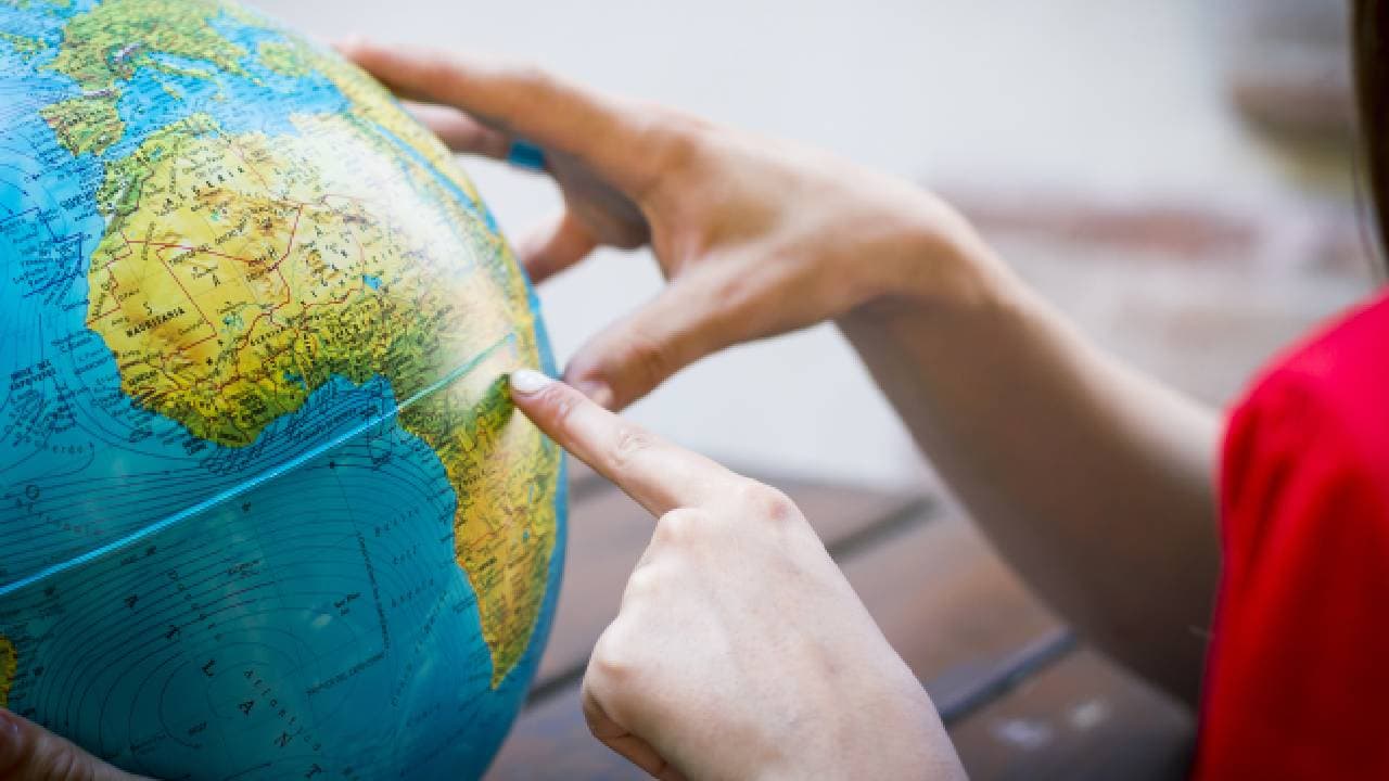 Teacher choosing a place on the globe where they can teach abroad