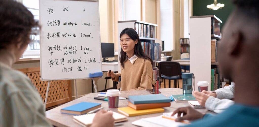 Young Asian Woman Talking To Group of Students at Table